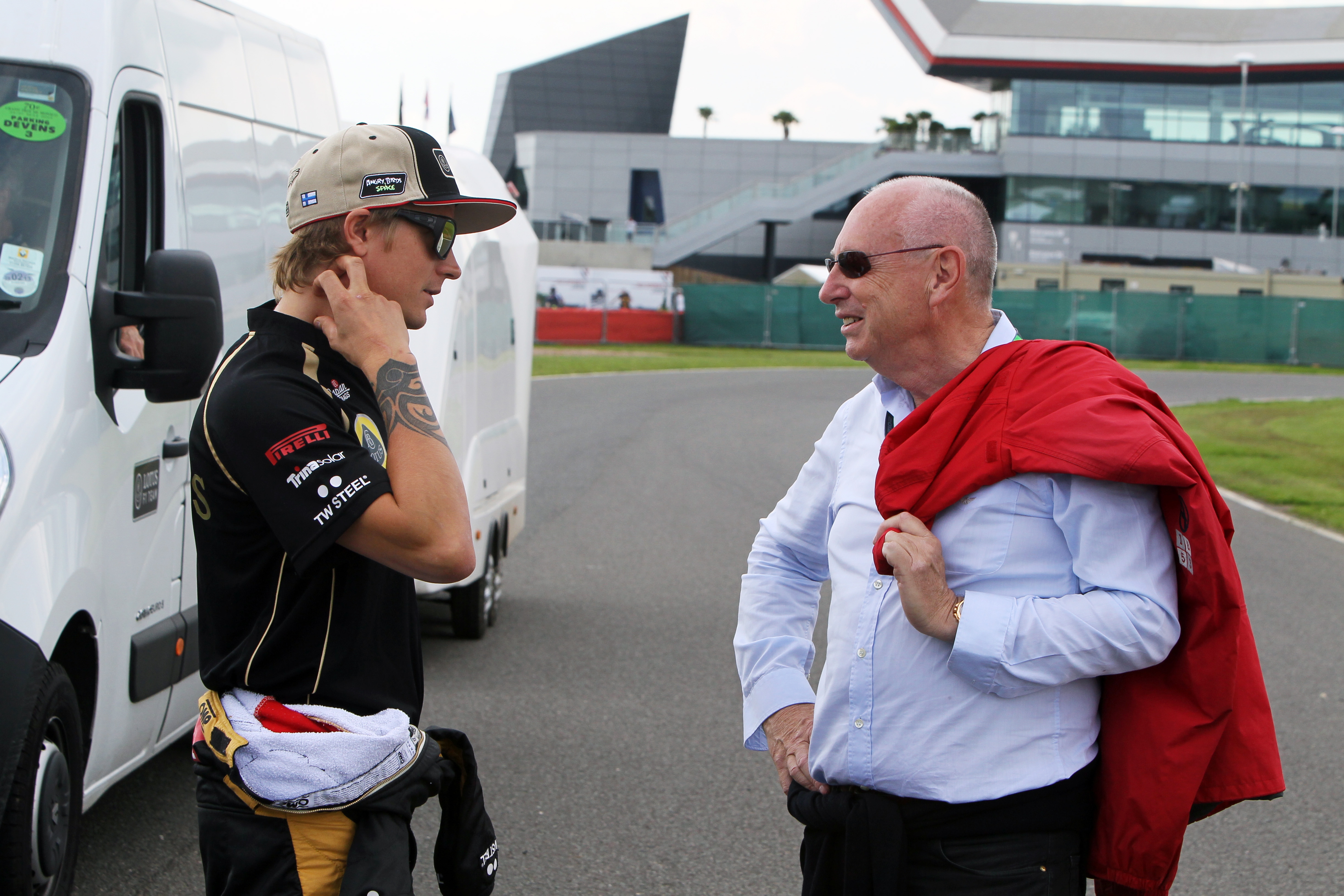 Peter Collins stands on the circuit to talk to kimi raikonnen at silverstone.